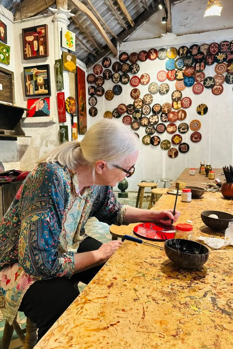 A luxury traveler engaging in a traditional Vietnamese lacquer painting workshop to support local art