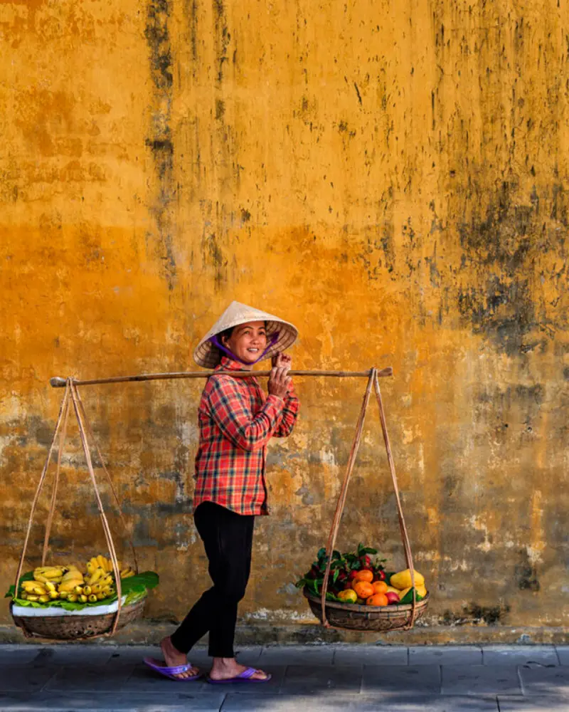 Authentic local life in Hoi An, with a Vietnamese street vendor against the ancient town’s iconic yellow walls