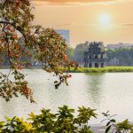 Luxury Trip to Vietnam sunrise over Hoan Kiem Lake with Turtle Tower and tree branches