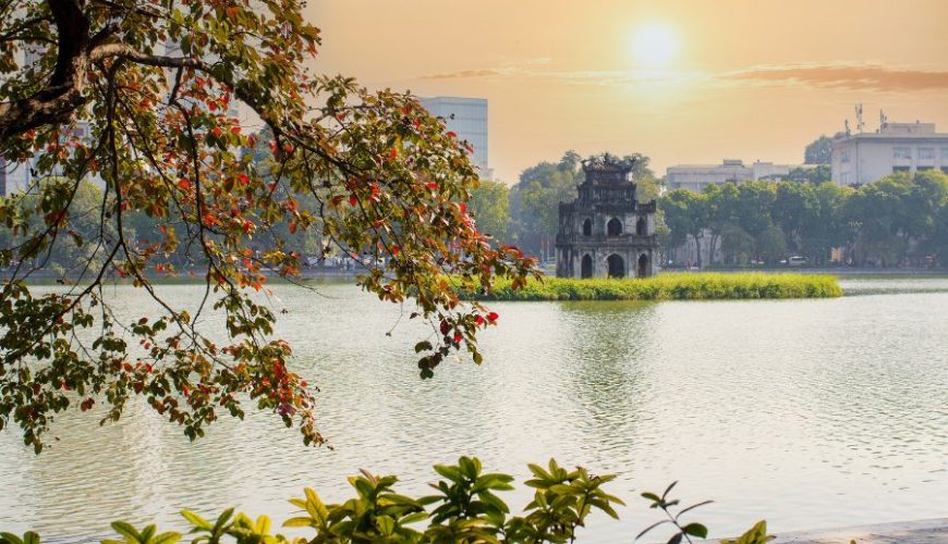 Luxury Trip to Vietnam sunrise over Hoan Kiem Lake with Turtle Tower and tree branches