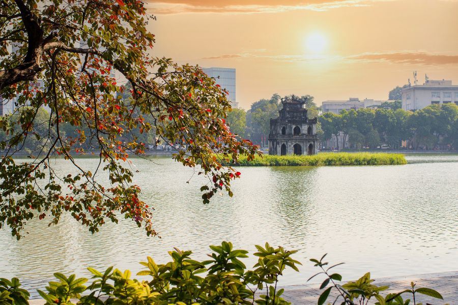Luxury Trip to Vietnam sunrise over Hoan Kiem Lake with Turtle Tower and tree branches