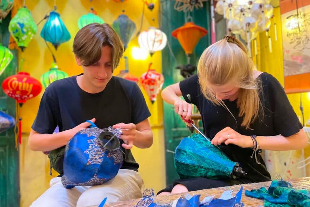 Visitors covering lantern frames with patterned fabric during a workshop in Hoi An