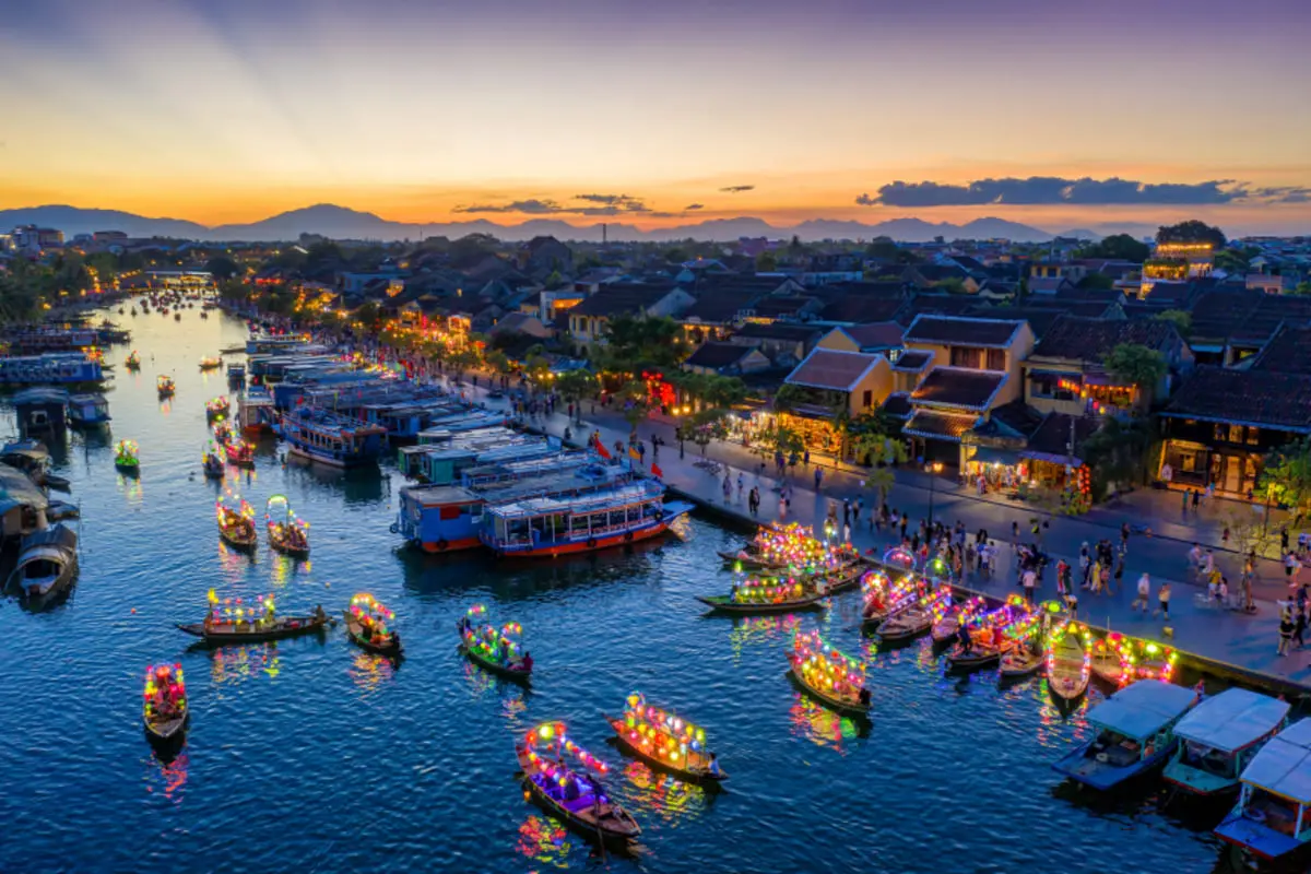 Lantern-lit boats and riverside buildings in Hoi An Ancient Town at dusk