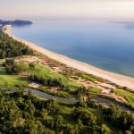 Aerial view of coastal golf fairways, bunkers and a beach beside the sea