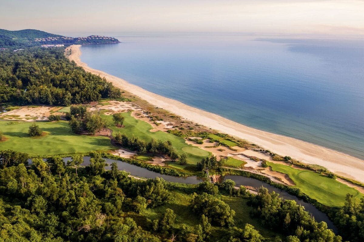 Aerial view of coastal golf fairways, bunkers and a beach beside the sea