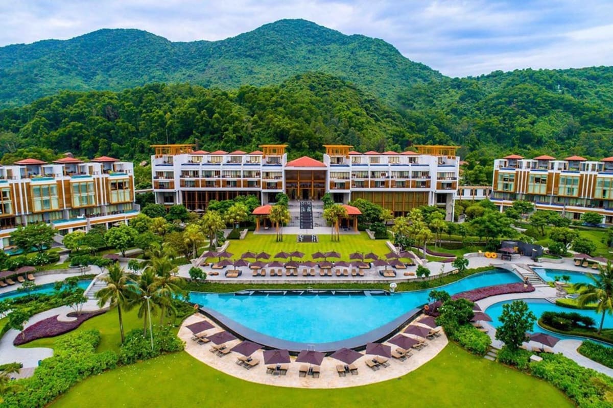 Resort swimming pool and sun loungers backed by forested mountains