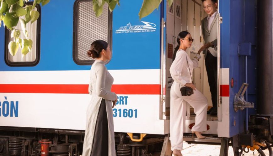 vietnam luxury train boarding scene, attendant assisting elegant passenger at carriage door beside blue-white carriage